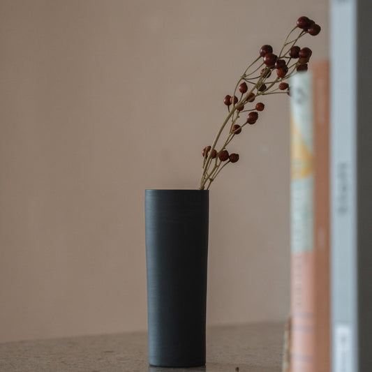 Japanse bloemenvaas "Cylinder" in zwart, gestyled op een sidetable, console-scène.