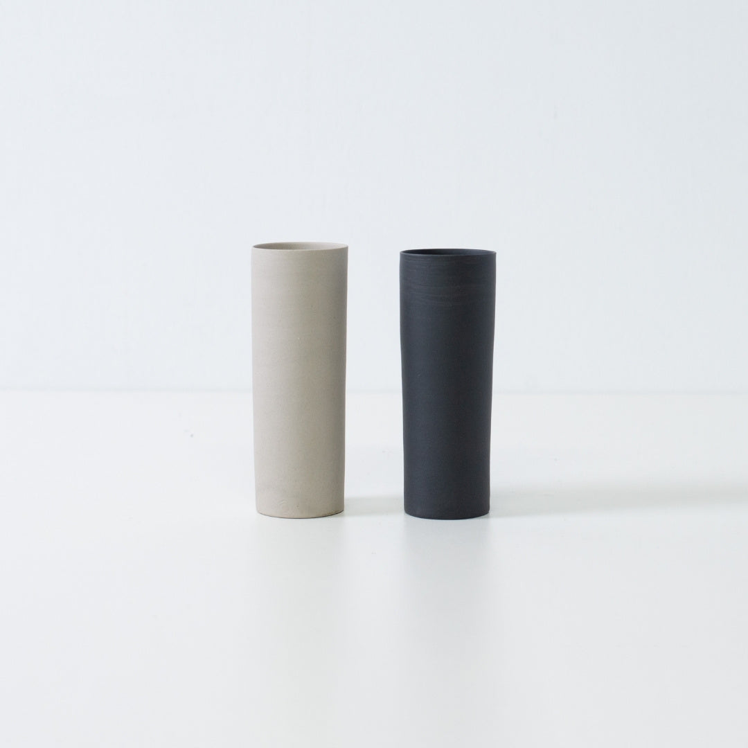 A pair of black and white Japanese flower vases standing together in a minimalist zen display of Banko yaki art.
