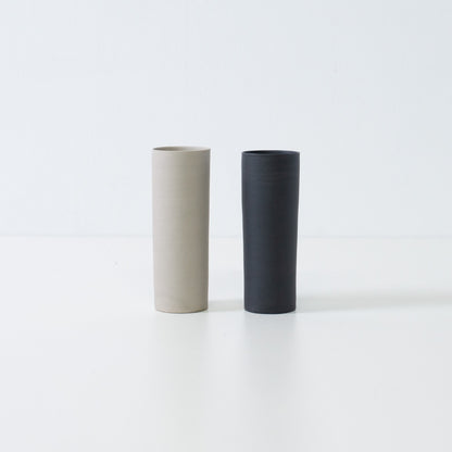 A pair of black and white Japanese flower vases standing together in a minimalist zen display of Banko yaki art.