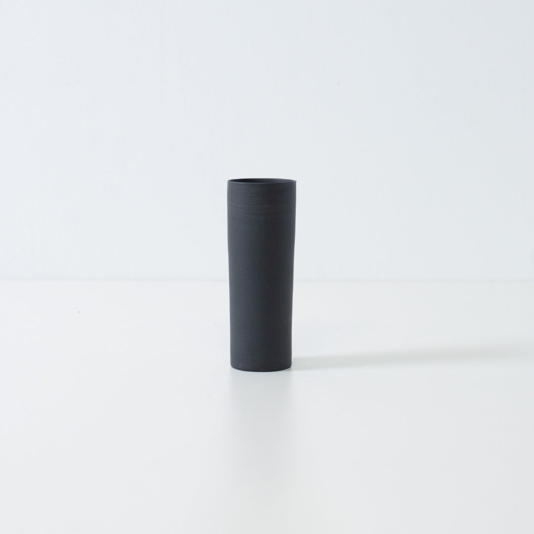 A handcrafted matte black Japanese flower vase in a minimalist cylinder shape for zen ikebana and single blooms.