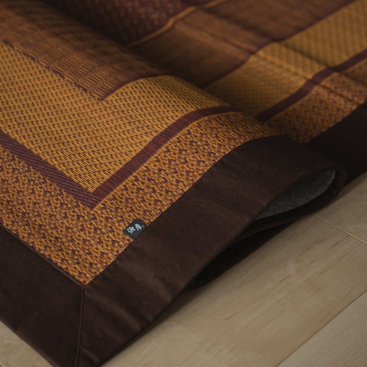 Japanese burgundy rush tatami area rug folded on a wood floor, offering an elegant pattern for Japanese decor.