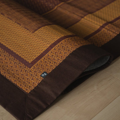Japanese burgundy rush tatami area rug folded on a wood floor, offering an elegant pattern for Japanese decor.