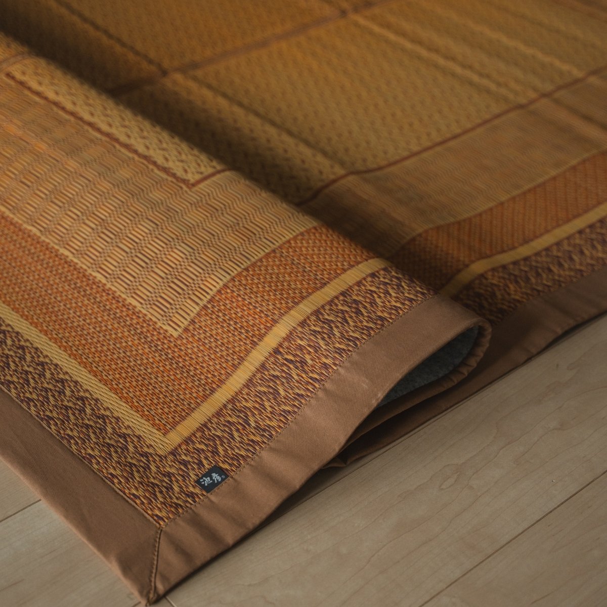 Japanese natural beige rush tatami area rug folded on a wood floor, offering a geometric pattern for Japanese decor.