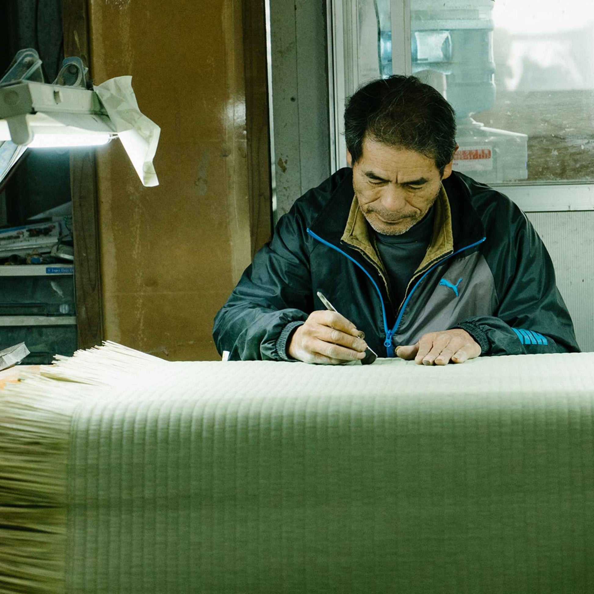 Japanese artisan skillfully crafting a traditional tatami mat in a workshop preserving history.