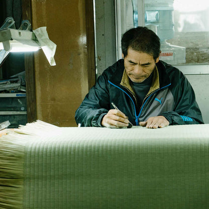 Japanese artisan skillfully crafting a traditional tatami mat in a workshop preserving history.