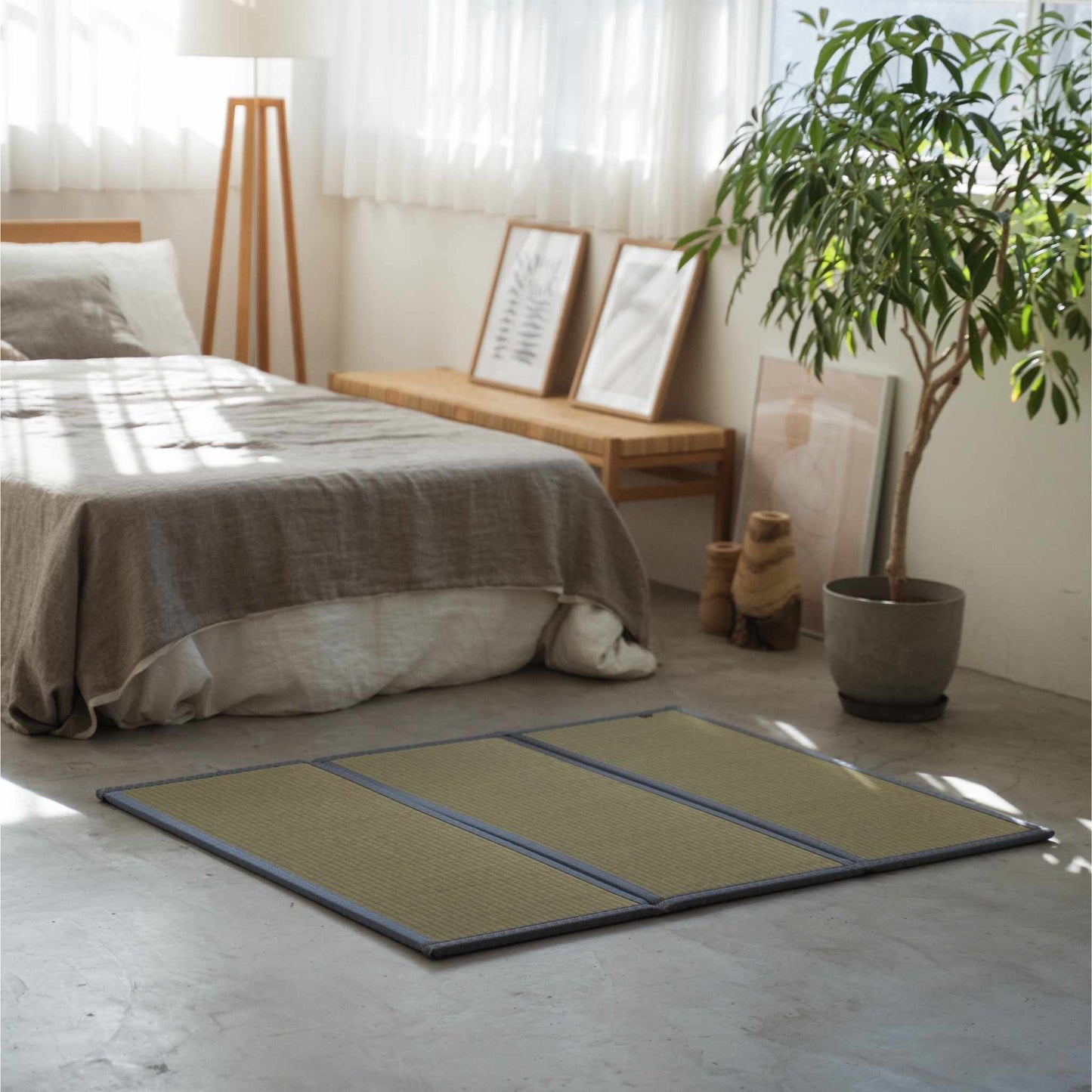 Three panel tatami mat placed on a concrete bedroom floor creating a compact personal meditation sanctuary.