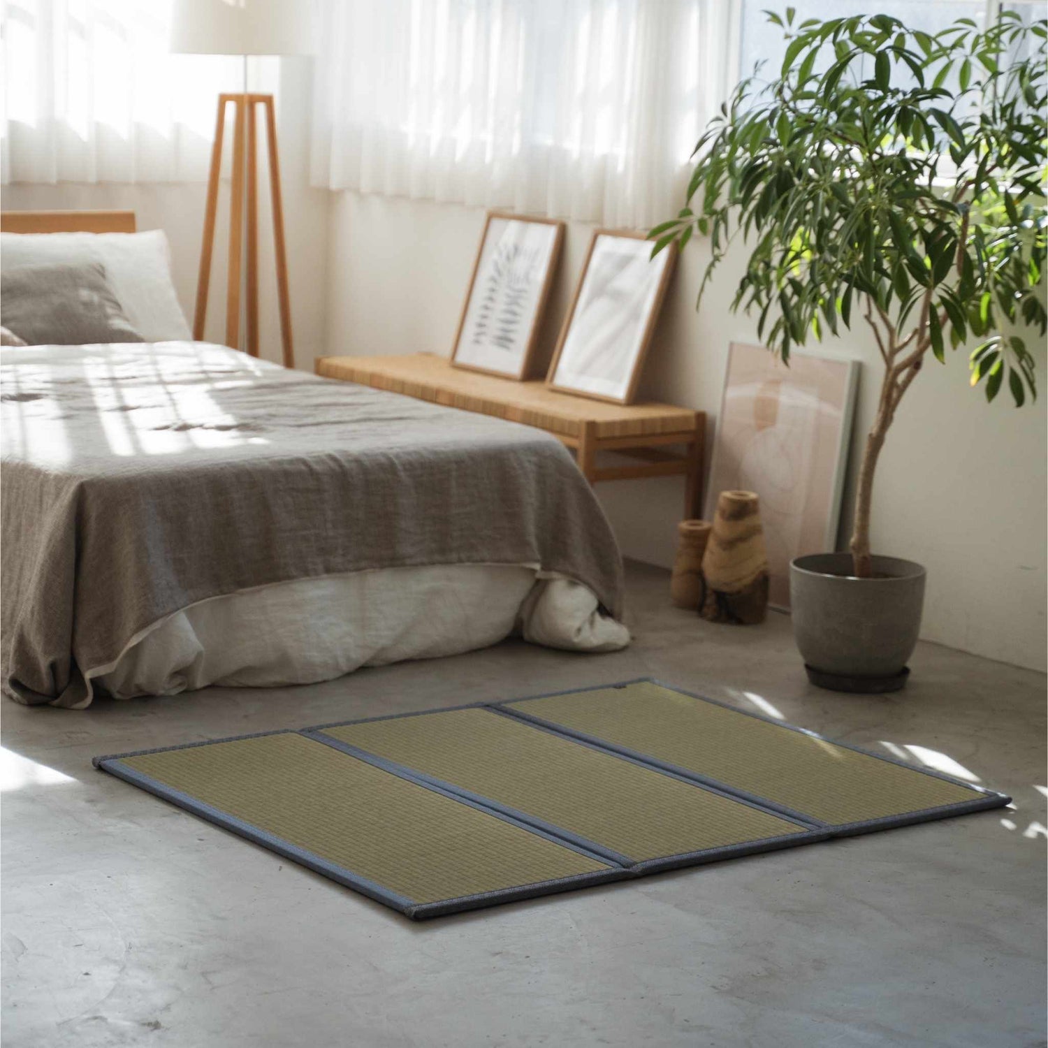 Three panel tatami mat placed on a concrete bedroom floor creating a compact personal meditation sanctuary.