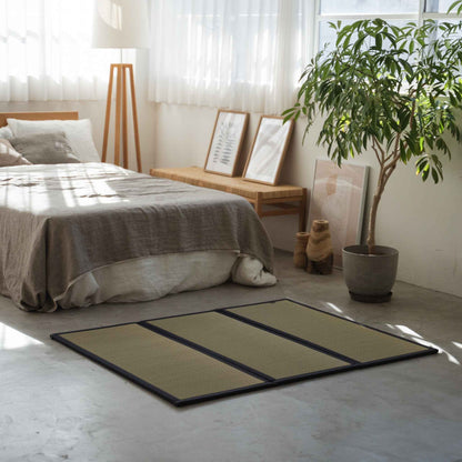 Compact three panel tatami mat placed on a concrete bedroom floor creating a cozy meditation space.