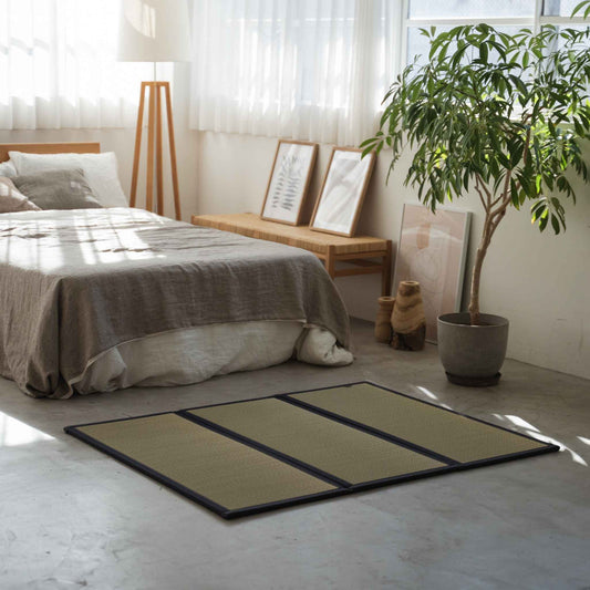 Compact three panel tatami mat placed on a concrete bedroom floor creating a cozy meditation space.