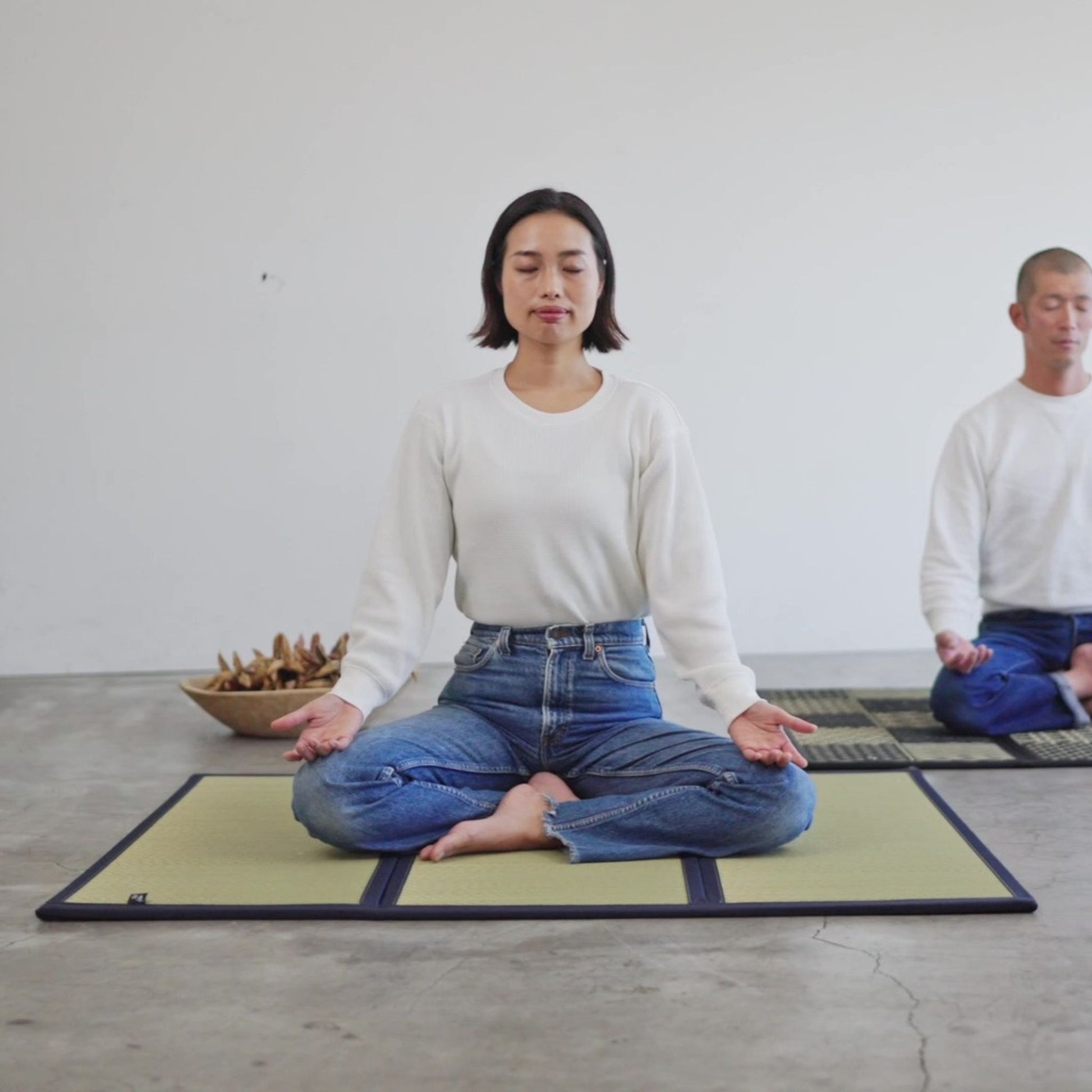 Woman meditating on a smooth undyed tatami mat practicing mindfulness in a calm and minimal space.