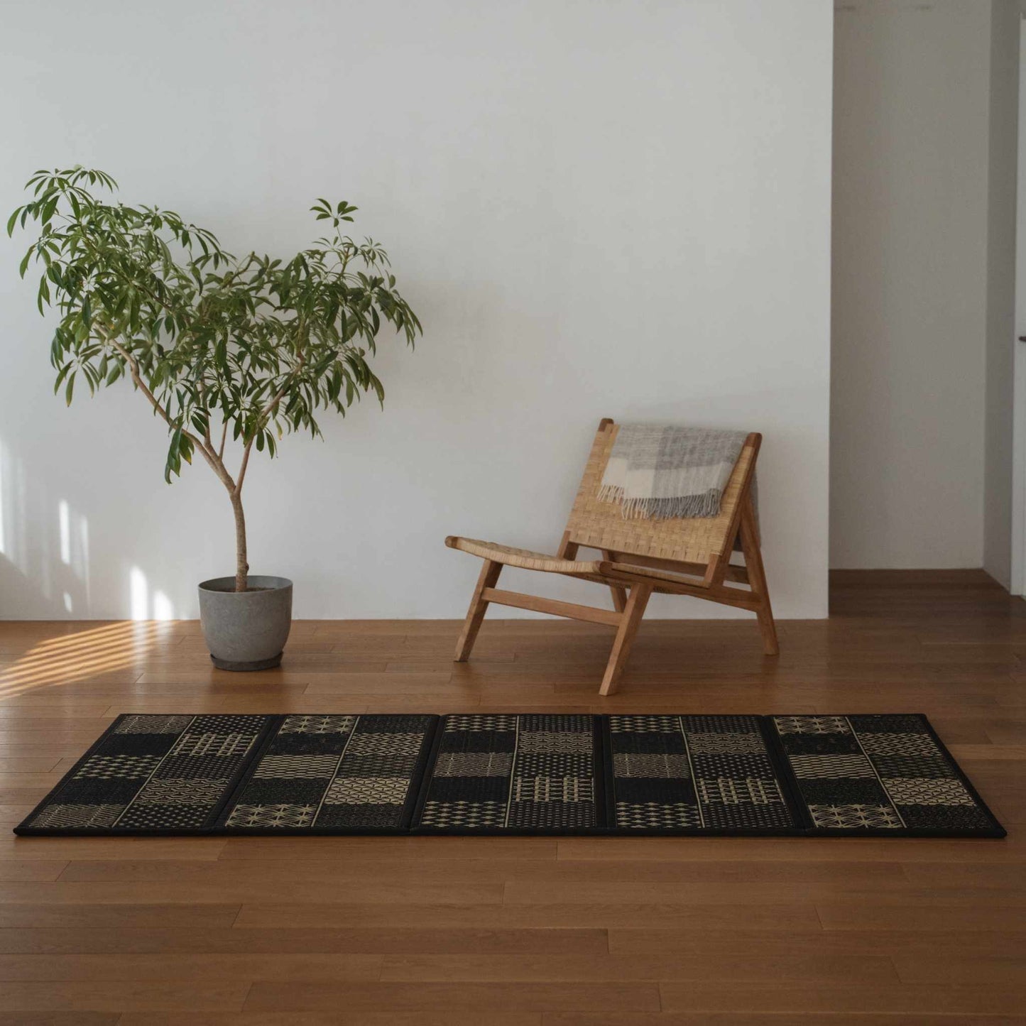 Long black tatami mat with geometric patterns on a living room floor creating a sophisticated zen decor atmosphere.
