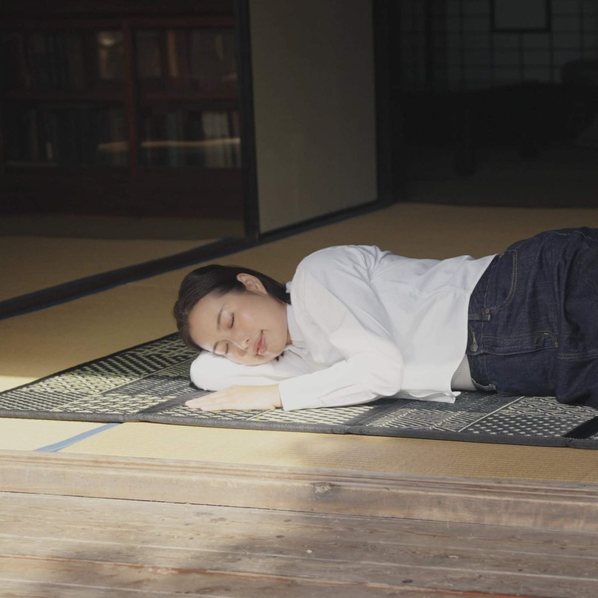 "Femme dormant sur un tatami Edokomon noir servant de base respirante et confortable pour le repos."