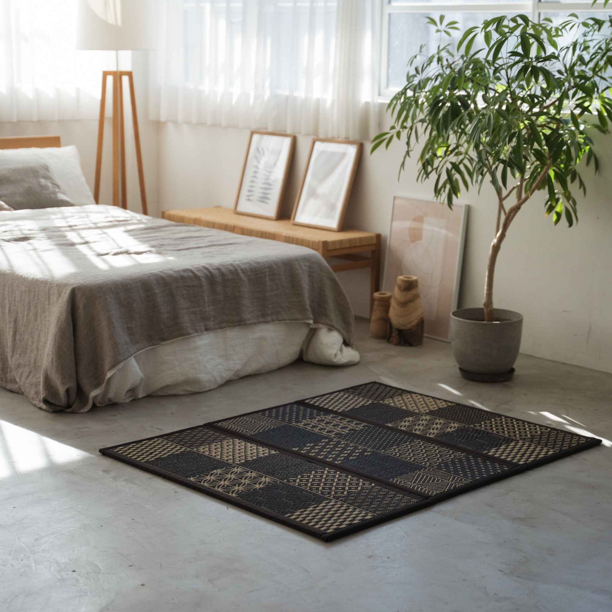Sort mønstret tatami-måtte placeret på et betongulv i soveværelset, der tilbyder et stilfuldt og åndbart rum til meditation.