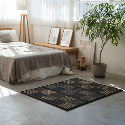 Black patterned tatami mat placed on a concrete bedroom floor offering a stylish and breathable space for meditation.