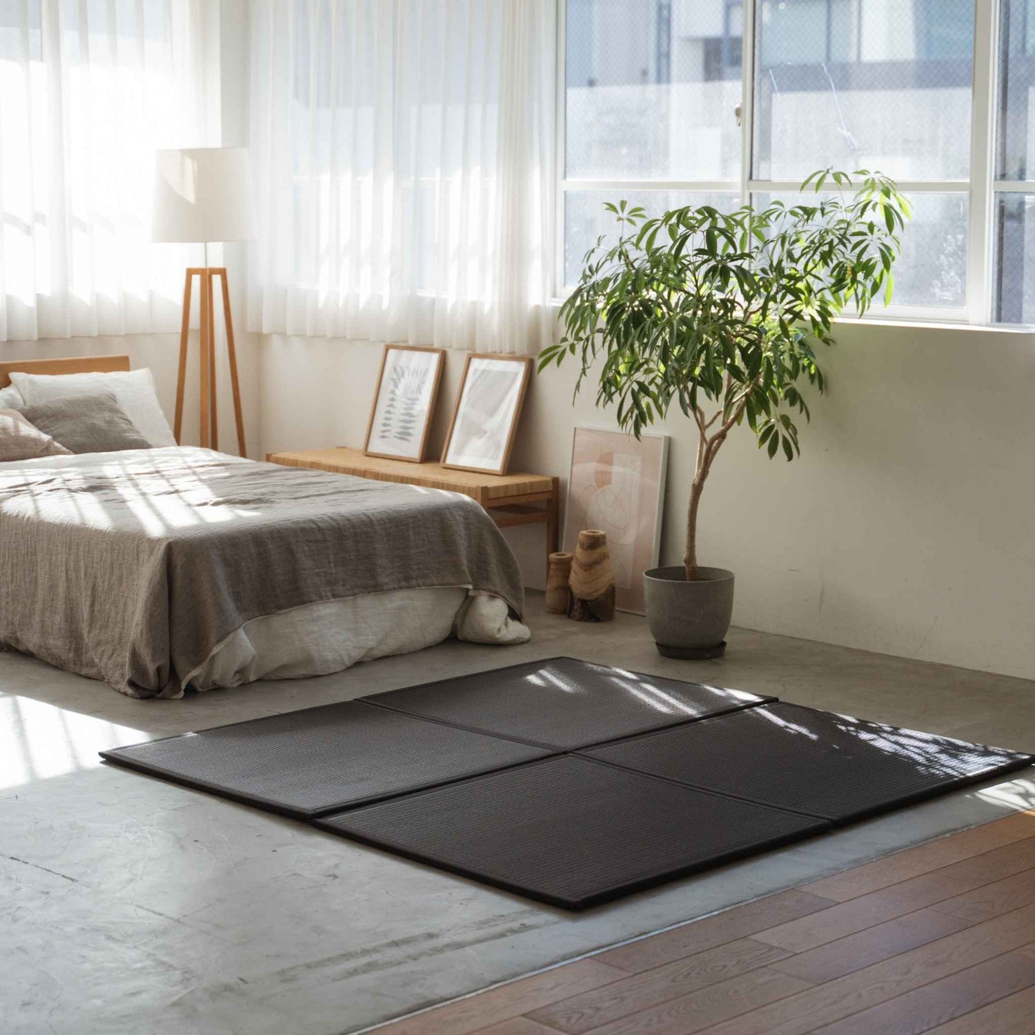 Black square tatami mats placed on a concrete bedroom floor creating a stylish and stain-proof meditation corner.