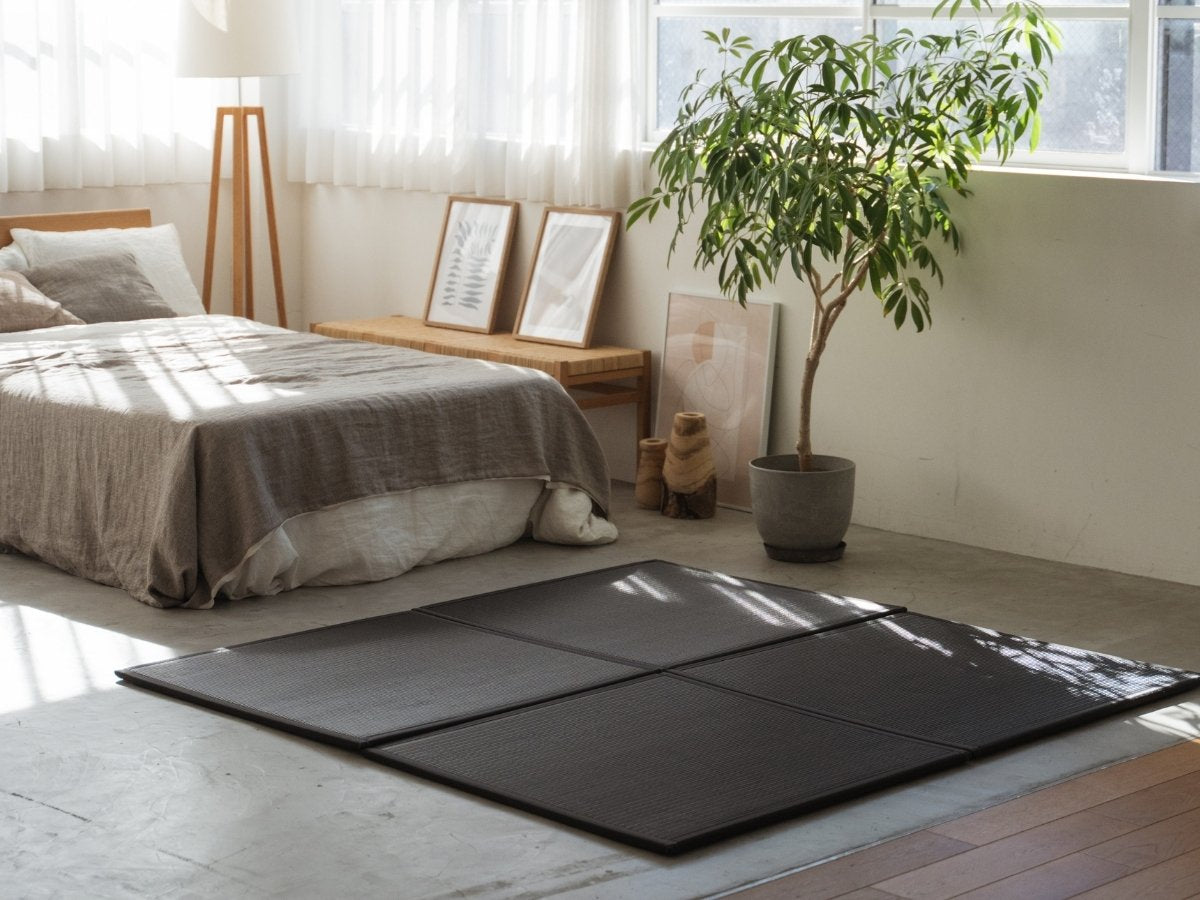 Black square tatami mats placed on a concrete bedroom floor creating a stylish and stain-proof meditation corner.