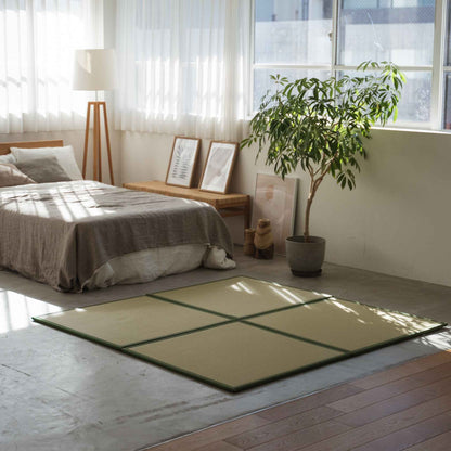 Green square tatami mats arranged on a concrete bedroom floor creating a stylish and stain-proof meditation corner.