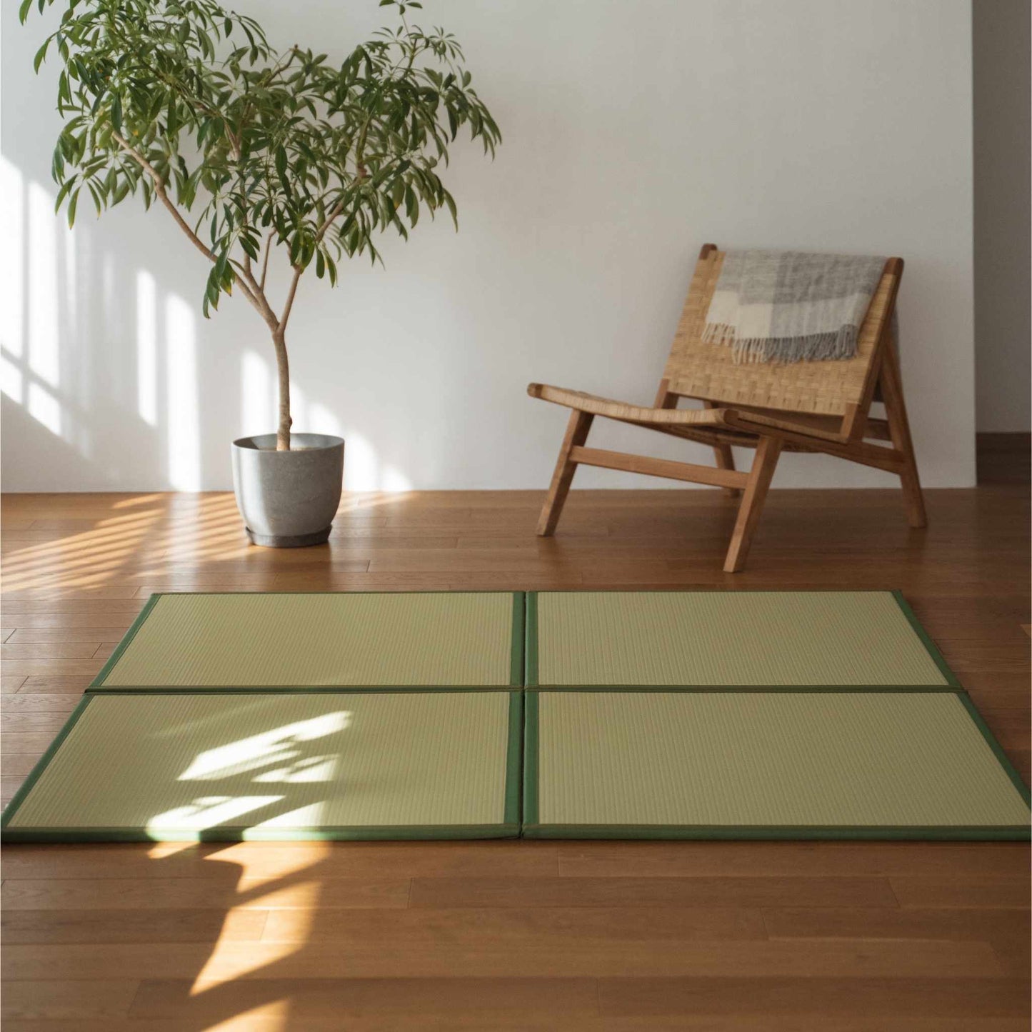 Four green square tatami mats laid on a wooden living room floor serving as a durable zen area rug.
