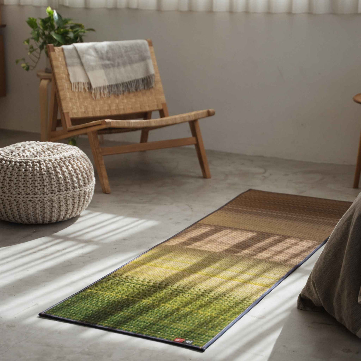 Green tatami yoga mat laid on a concrete floor next to a chair offering a zen decor vibe for wellness.