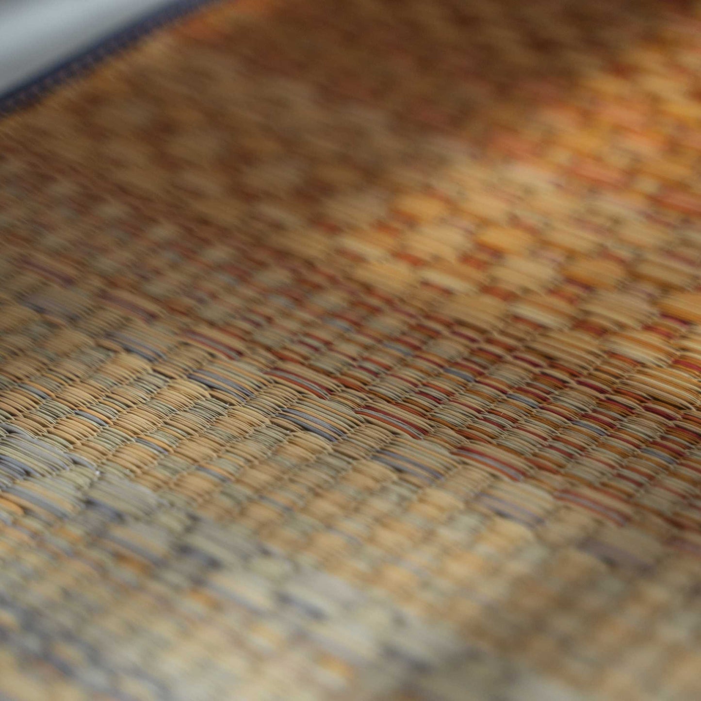 Close up of red tatami yoga mat surface showing authentic rush grass weave for natural meditation.