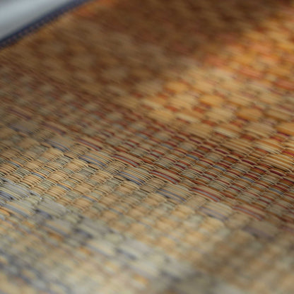 Close up of red tatami yoga mat surface showing authentic rush grass weave for natural meditation.