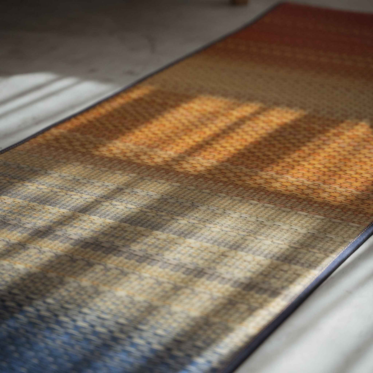 Angled view of a Japanese tatami yoga mat displaying a beautiful red gradient design on the floor.