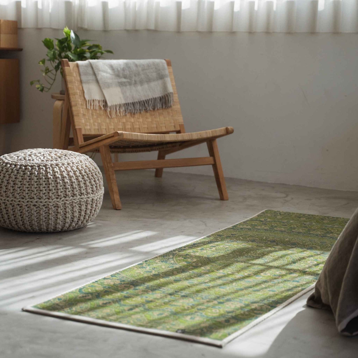 Green mandala tatami mat placed on a concrete living room floor creating a serene meditation space.