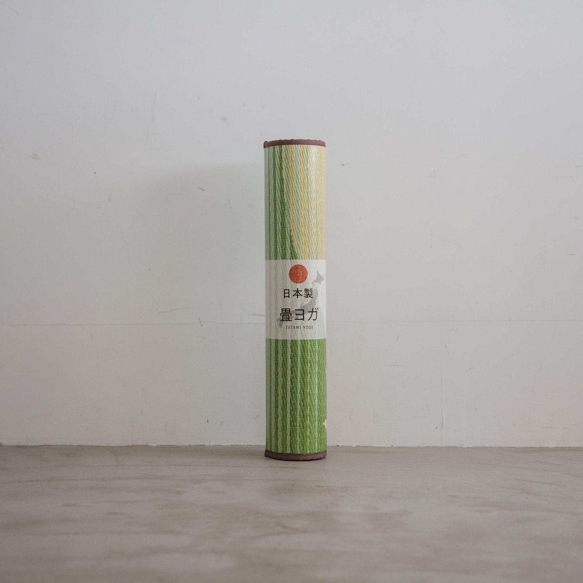 Rolled sakura tatami mat standing upright against a white wall showing natural rush grass texture for japanese decor.