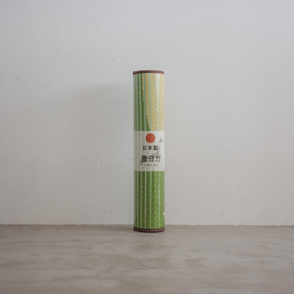 Rolled sakura tatami mat standing upright against a white wall showing natural rush grass texture for japanese decor.