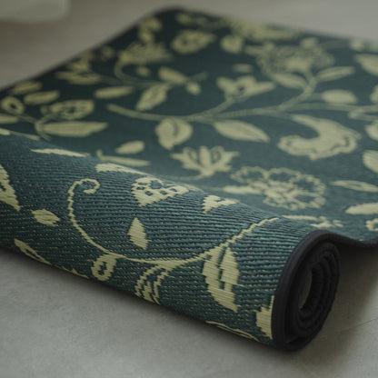 Japanse Tatami Yogamat "Sarasa" Navy gedeeltelijk opgerold op een grijze vloer, met de natuurlijke matgras weving en patroon.