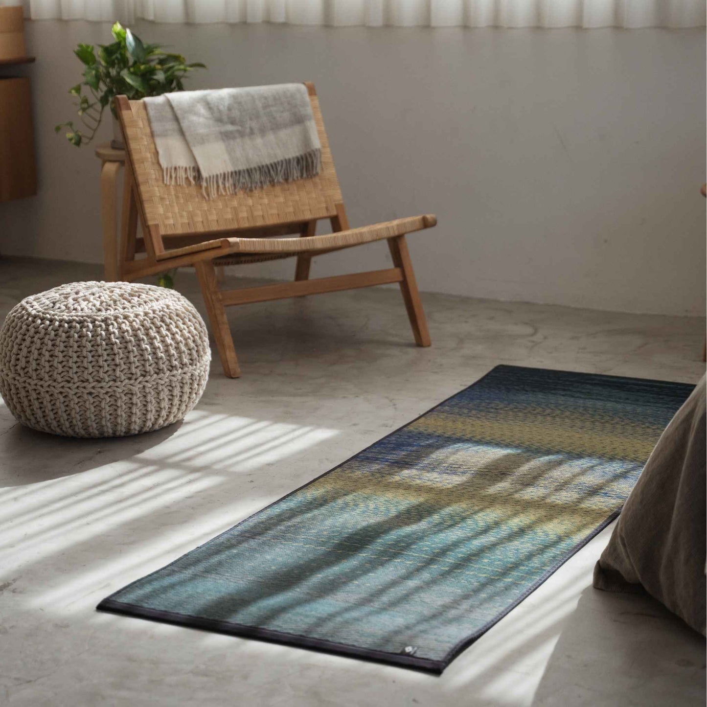 Blue tatami yoga mat laid on a concrete living room floor serving as a stylish zen decor accent.