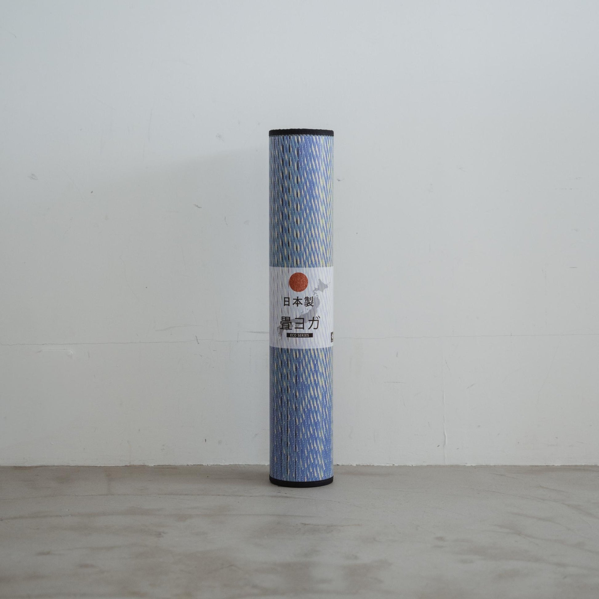 Rolled up blue tatami yoga mat standing upright highlighting its portability and Japanese quality.