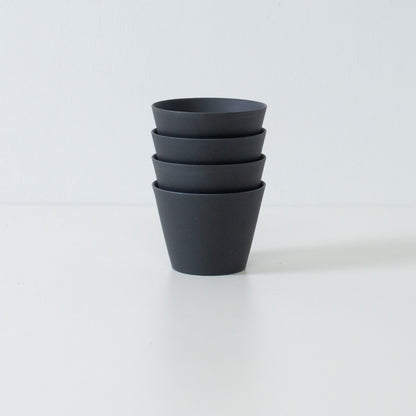 Stack of four black ensui japanese tea cups displaying the space saving design of this modern stoneware set