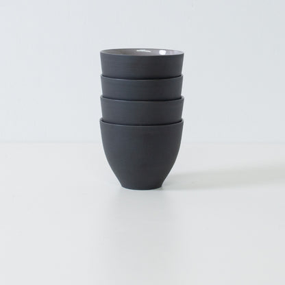 Stack of four black japanese tea cups forming a compact modern japanese tea set ready for storage