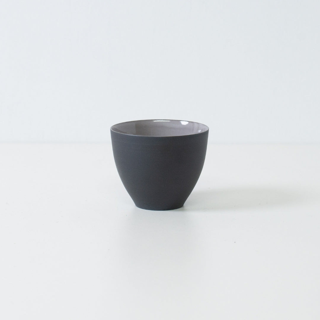 Side view of matte black japanese tea cups f-shape chawan standing on white surface displaying modern banko ware silhouette