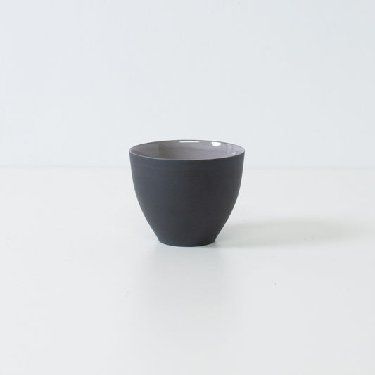 Side view of matte black japanese tea cups f-shape chawan standing on white surface displaying modern banko ware silhouette