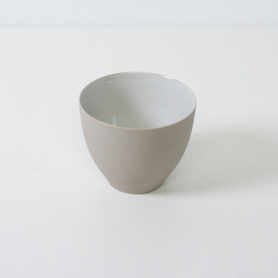 High angle shot of a white japanese tea cup highlighting the contrast between the unglazed exterior and glazed interior
