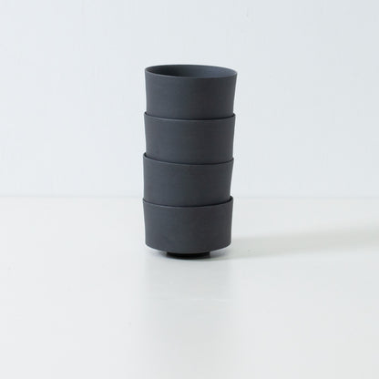 Stack of four black japanese tea cups demonstrating storage efficiency and straight cylinder shape.