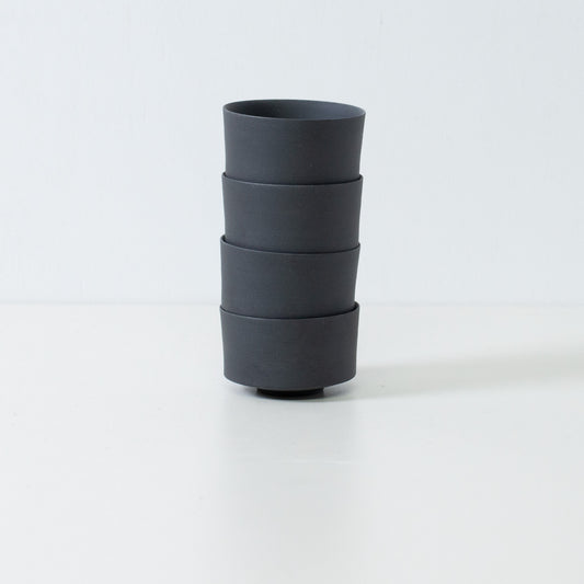 Stack of four black japanese tea cups demonstrating storage efficiency and straight cylinder shape.
