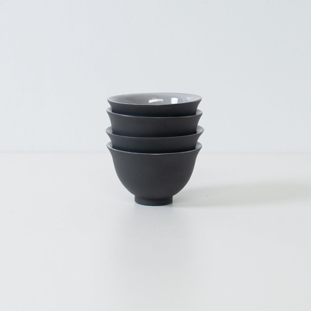 Stack of four black japanese tea cups demonstrating storage efficiency and kumidashi shape.