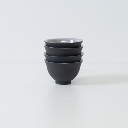 Stack of four black japanese tea cups demonstrating storage efficiency and kumidashi shape.
