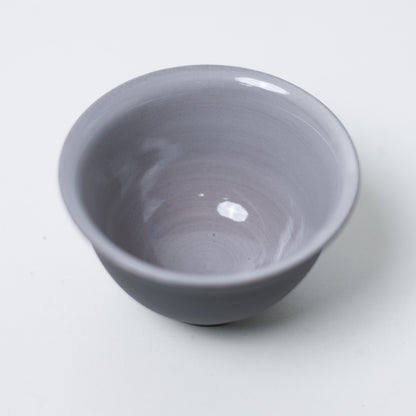 Top down view inside kumidashi japanese tea cup showing glossy grey glaze texture against black clay rim.