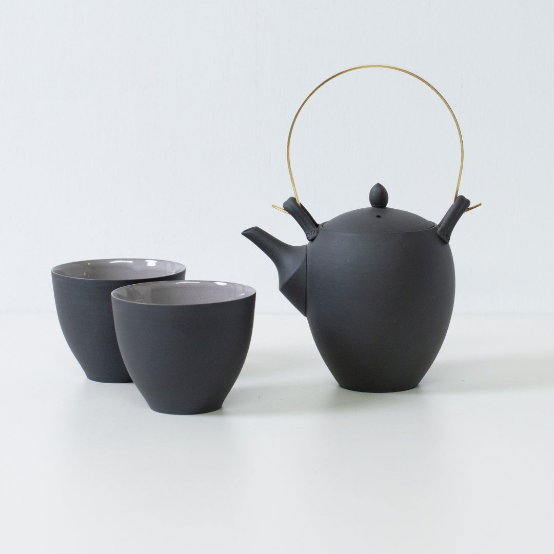 Modern japanese tea set with a black donguri teapot and curved f shape tea cups designed for a comfortable grip