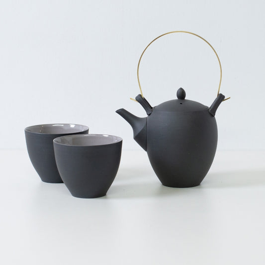 Modern japanese tea set with a black donguri teapot and curved f shape tea cups designed for a comfortable grip