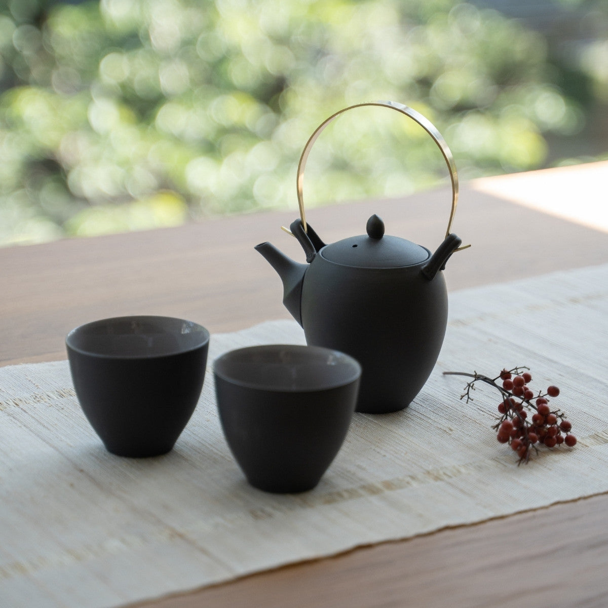 Traditional black Japanese tea set on a sunlit table for guests experiencing authentic hospitality.