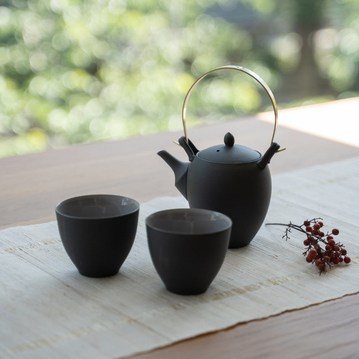 Black Japanese tea set with kyusu on a wooden table for tea lovers enjoying a modern zen ritual.