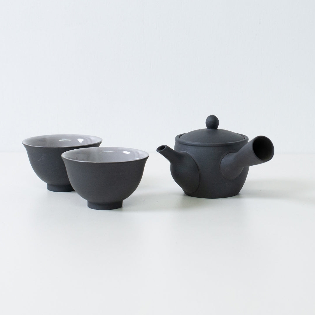 Black japanese tea set featuring fuyo kyusu teapot and kumidashi cups arranged on white surface for serving.