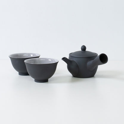 Black japanese tea set featuring fuyo kyusu teapot and kumidashi cups arranged on white surface for serving.