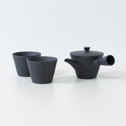 Japanese tea set featuring a black sencha kyusu teapot and two matte ensui chawan tea cups placed on a white table.