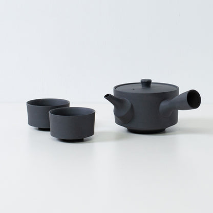 Matte black japanese tea set featuring a 350cc sencha kyusu and minimalist cylinder chawan cups on a white table